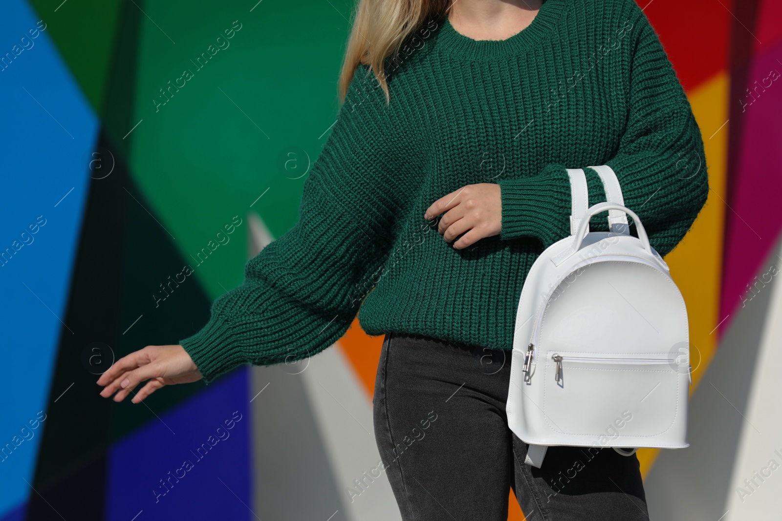 Photo of Young woman with stylish backpack near color wall, closeup