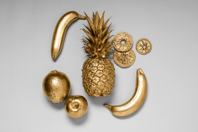 Different golden fruits on light grey background, flat lay