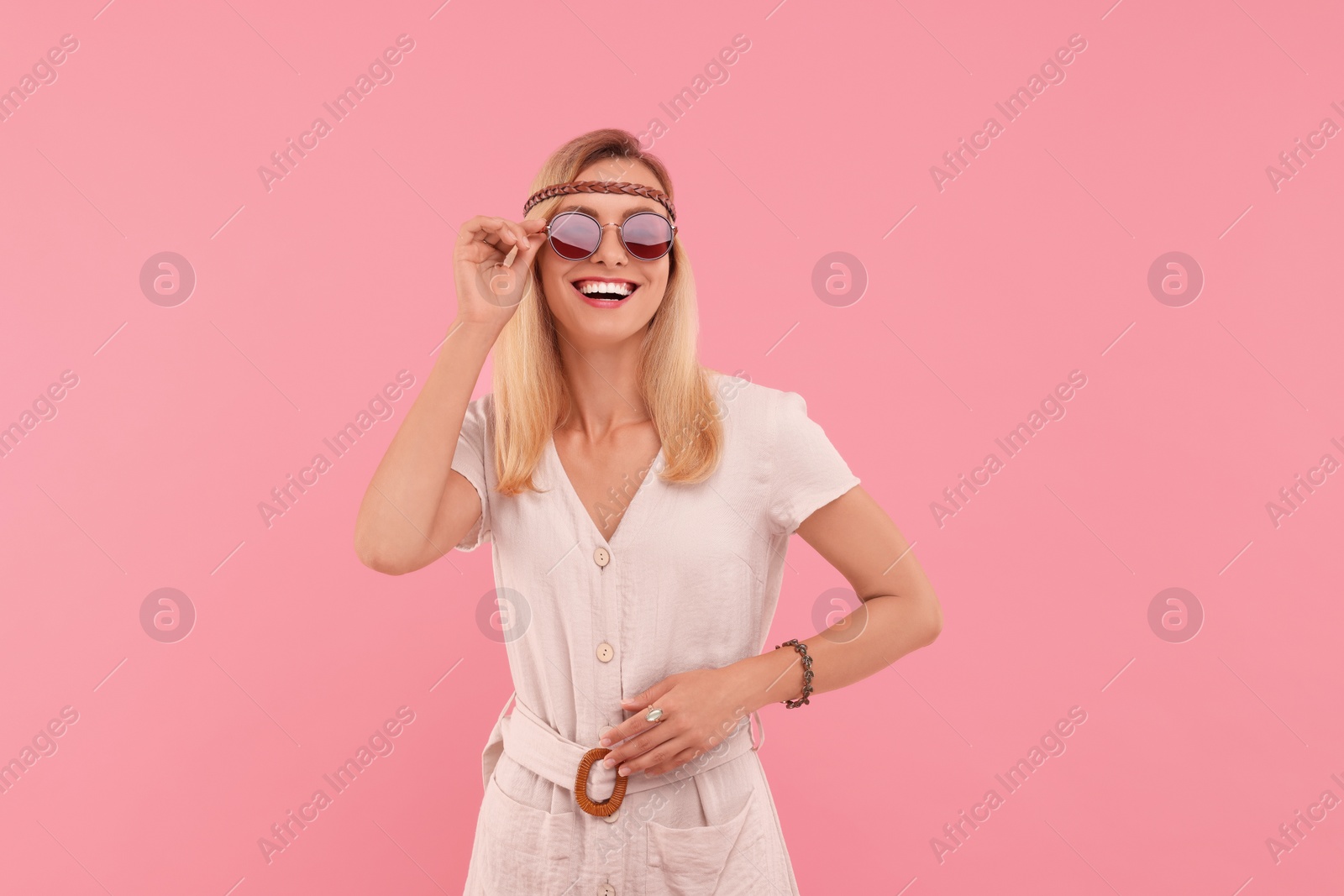 Photo of Portrait of smiling hippie woman in sunglasses on pink background