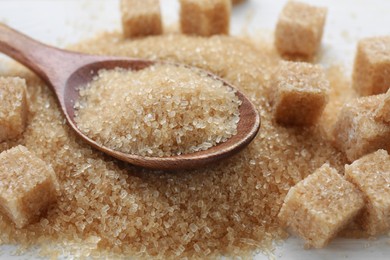 Different types of brown sugar on white table, closeup