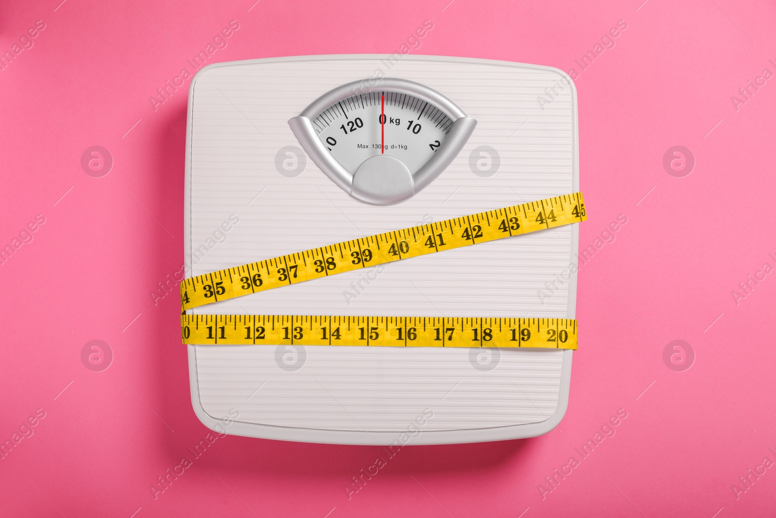 Photo of Weight loss concept. Scales and measuring tape on pink background, top view