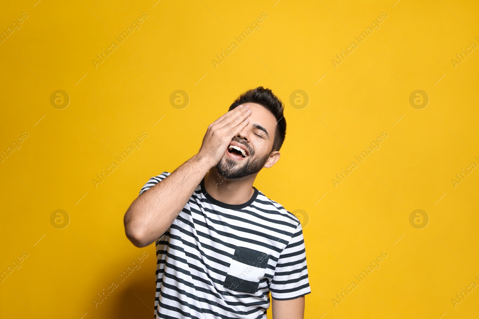 Photo of Young man laughing on yellow background. Funny joke