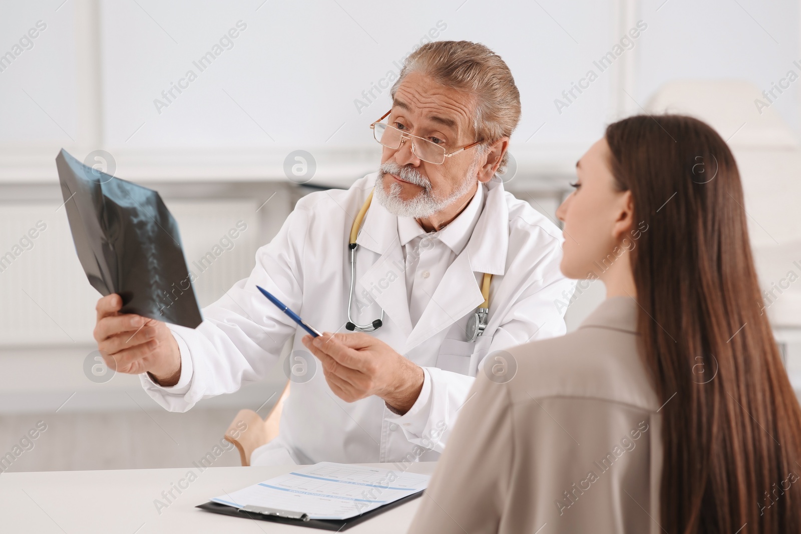 Photo of Orthopedist showing X-ray picture to patient in clinic