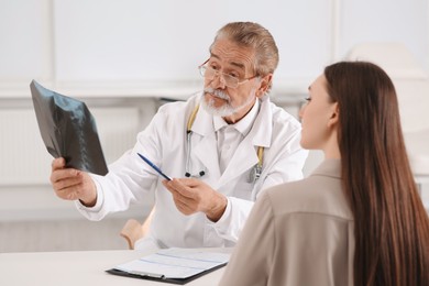 Orthopedist showing X-ray picture to patient in clinic