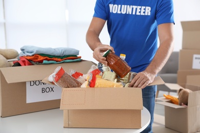 Photo of Male volunteer collecting donations at table indoors