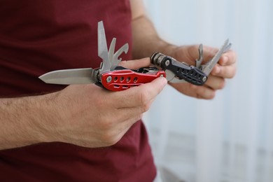 Photo of Man holding multitool on light background, closeup