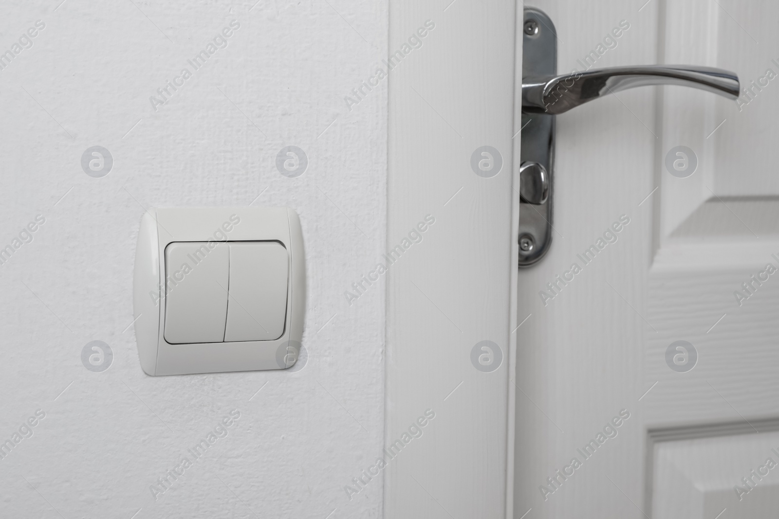 Photo of Modern light switch on white wall near door