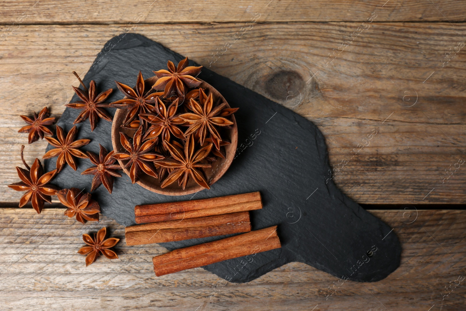 Photo of Aromatic cinnamon sticks and anise stars on wooden table, flat lay. Space for text