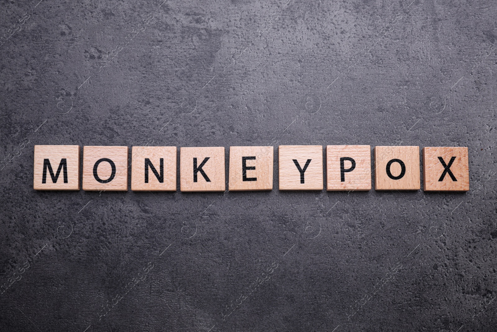 Photo of Word Monkeypox made of wooden squares on grey table, top view