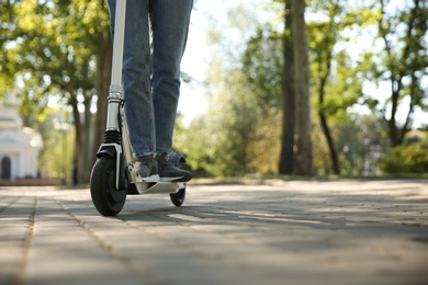 Woman riding electric kick scooter outdoors, closeup. Space for text