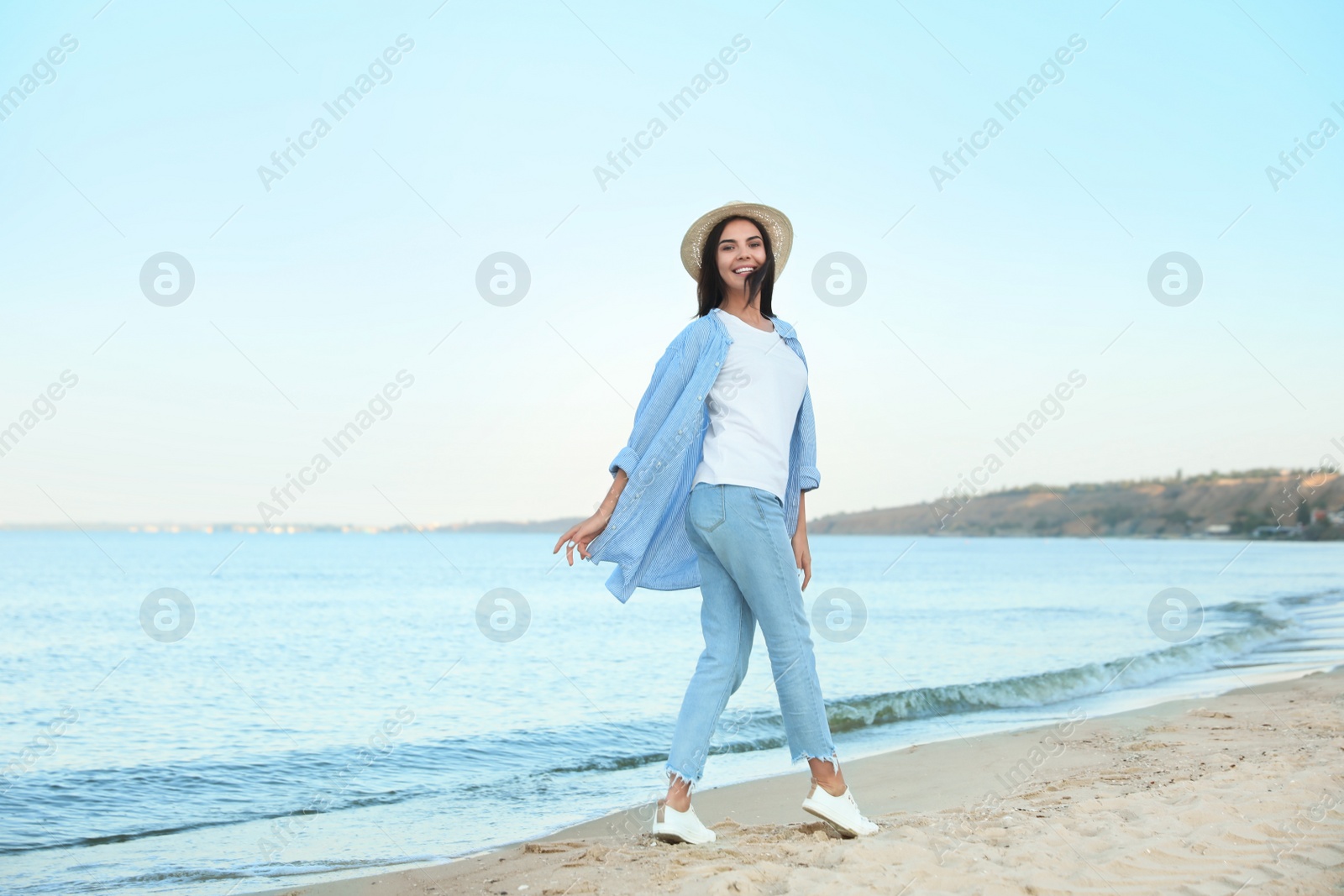 Photo of Beautiful young woman in casual outfit on beach