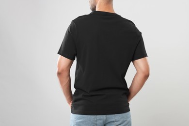 Photo of Man wearing black t-shirt on gray background, closeup