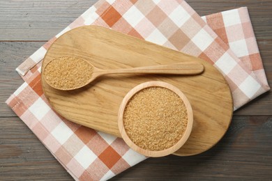 Photo of Brown sugar in bowl and spoon on wooden table, top view