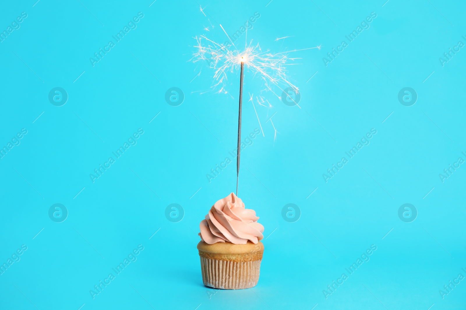 Photo of Birthday cupcake with sparkler on light blue background