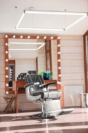 Stylish hairdresser's workplace with professional armchair and large mirror in barbershop. Interior design