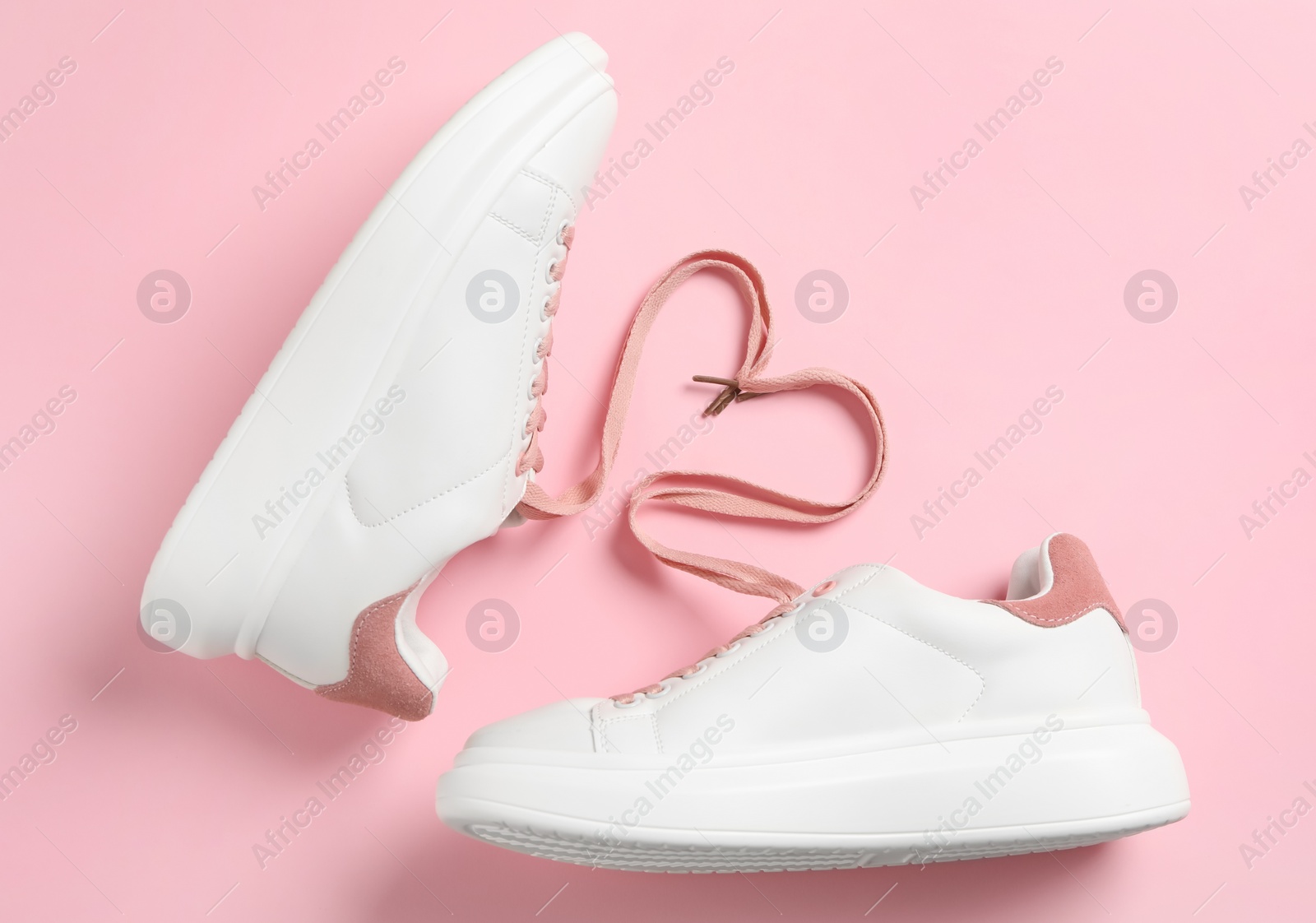 Photo of Pair of stylish shoes with laces on pink background flat lay