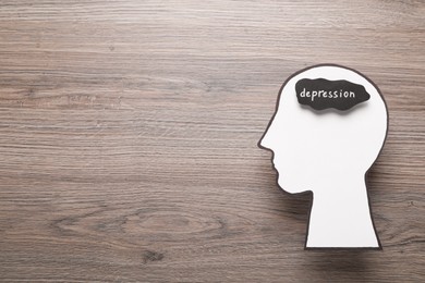 Photo of Human head cutout with word Depression on wooden table, top view. Space for text