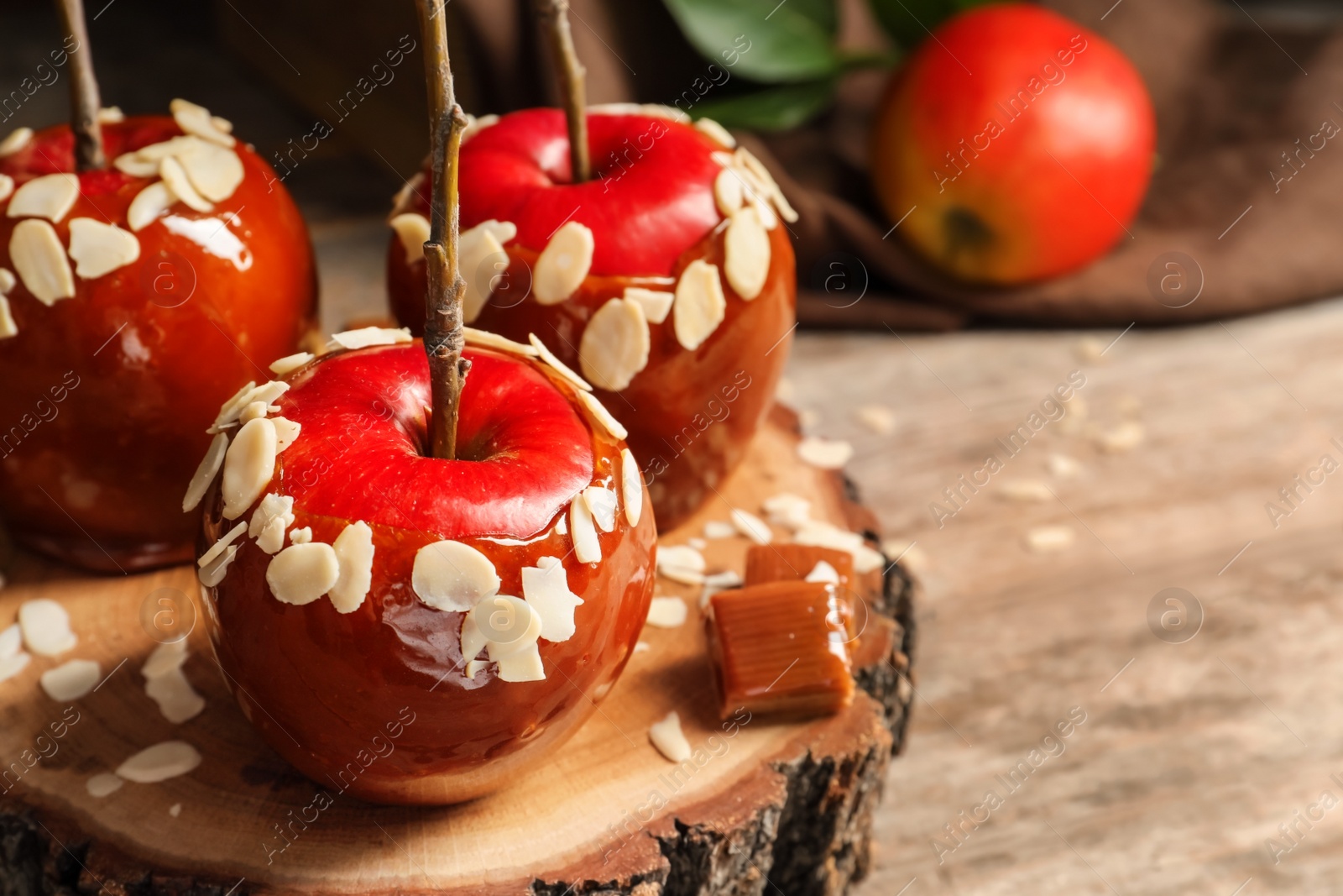 Photo of Delicious caramel apples on wooden serving board