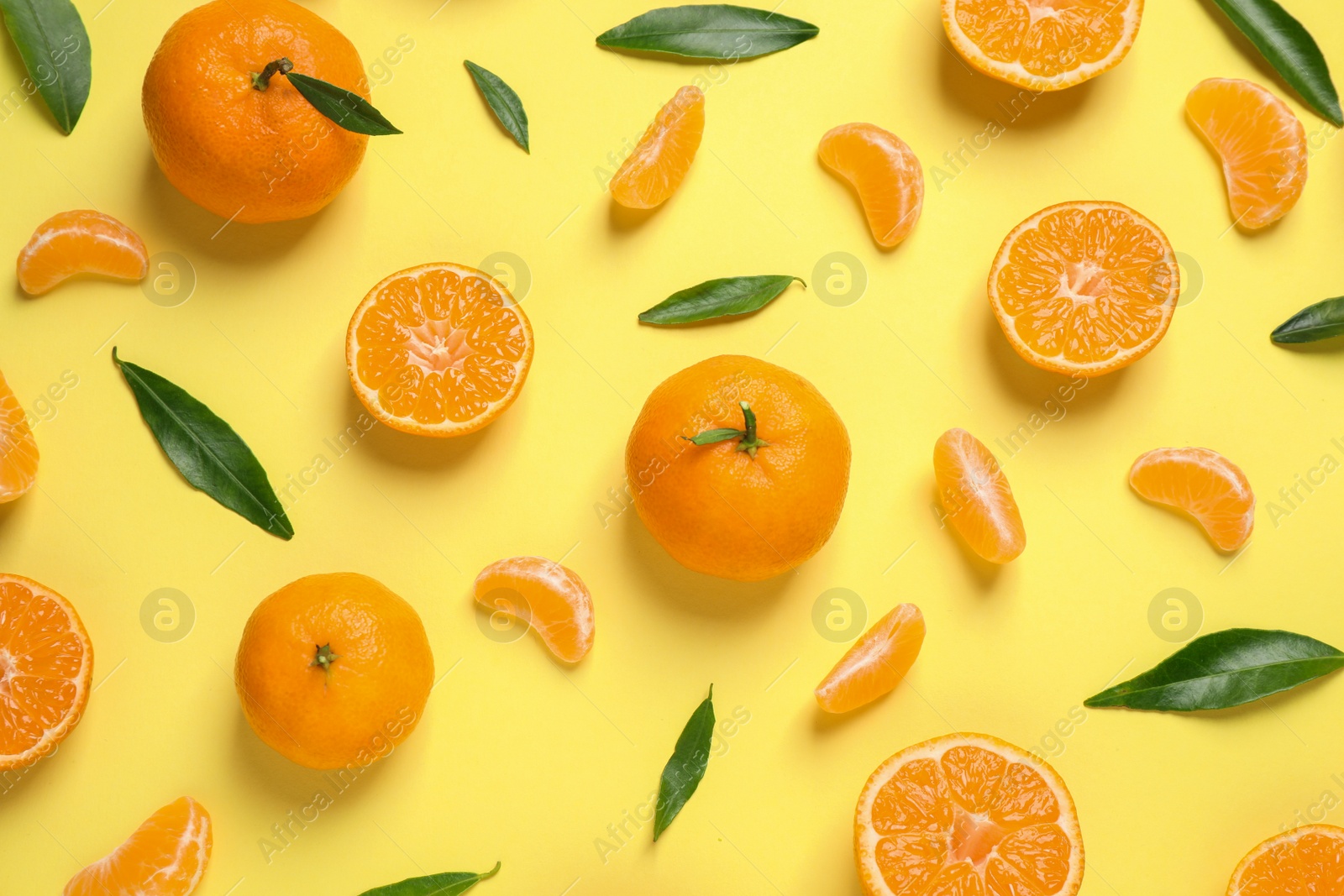 Photo of Flat lay composition with fresh ripe tangerines and leaves on light yellow background. Citrus fruit