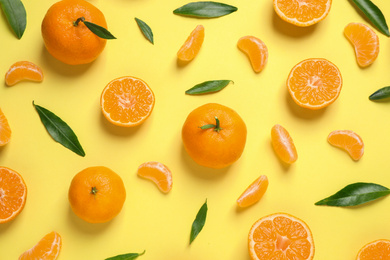 Photo of Flat lay composition with fresh ripe tangerines and leaves on light yellow background. Citrus fruit