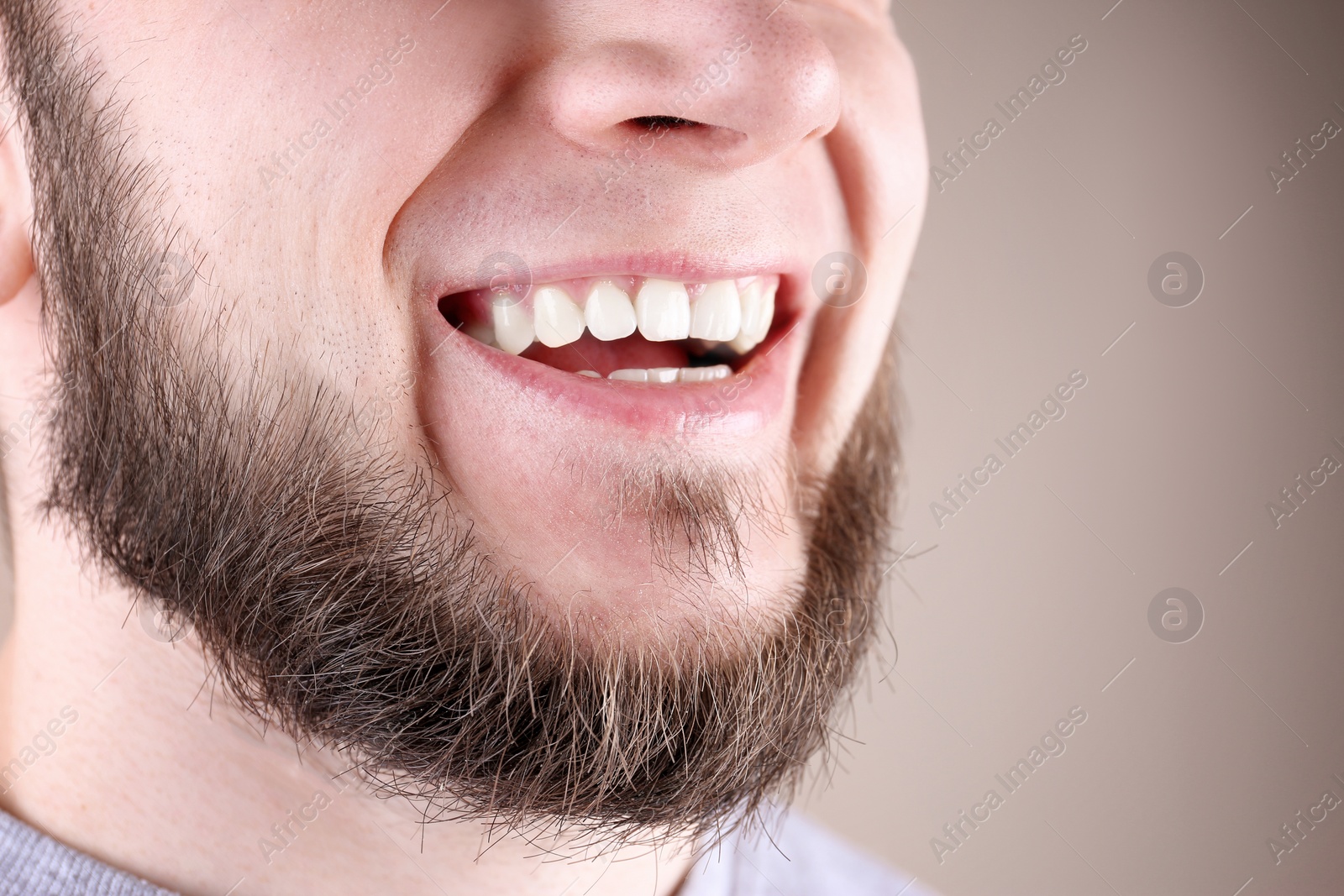 Photo of Young man with healthy teeth and beautiful smile on color background, closeup. Space for text