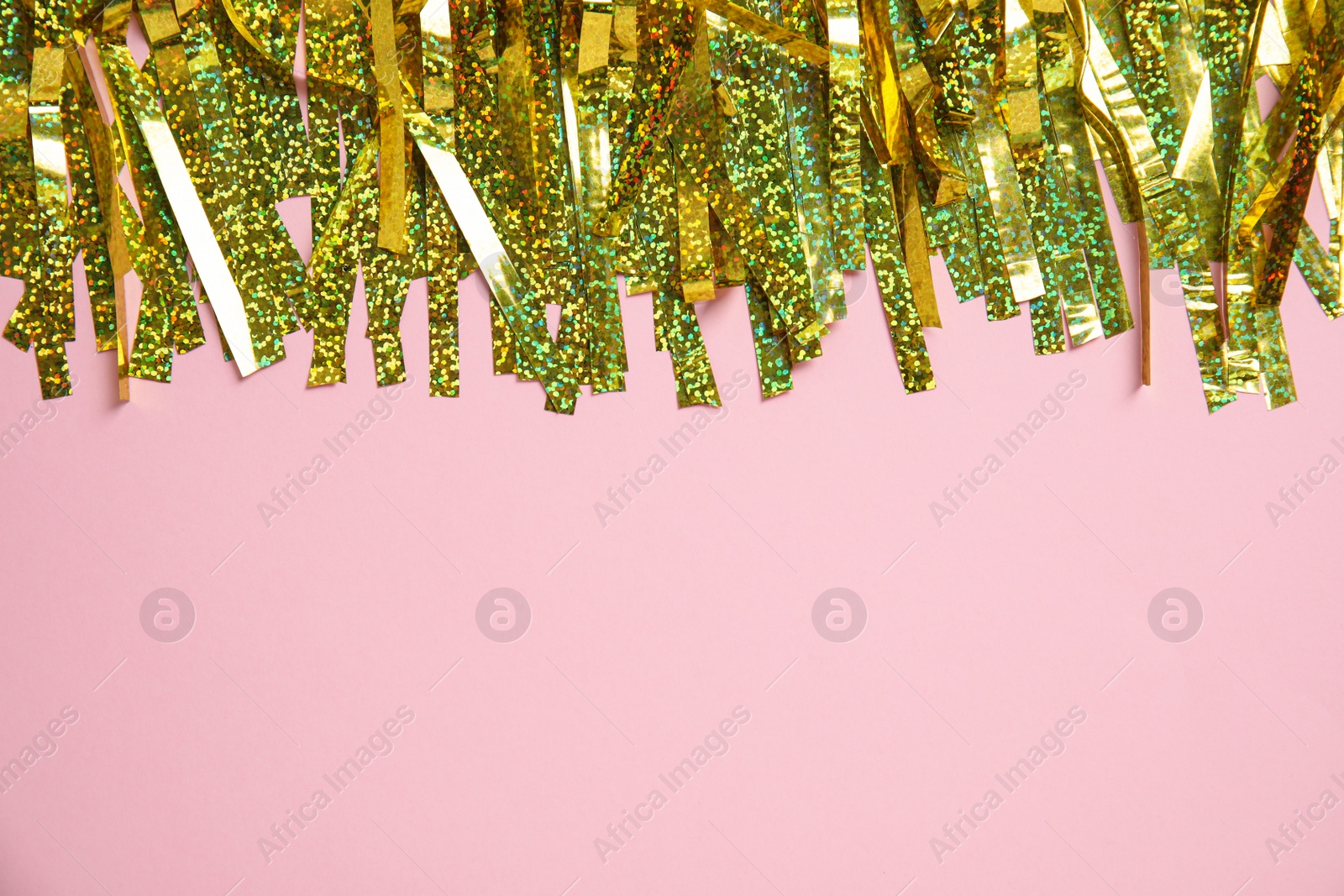 Photo of Golden tinsel on pink background, top view. Space for text