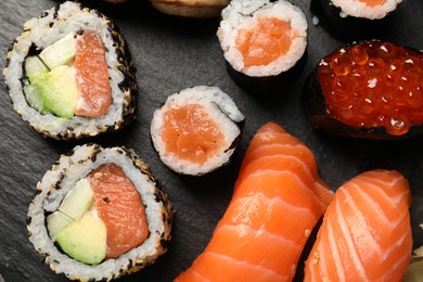 Set of delicious sushi rolls on slate board, top view