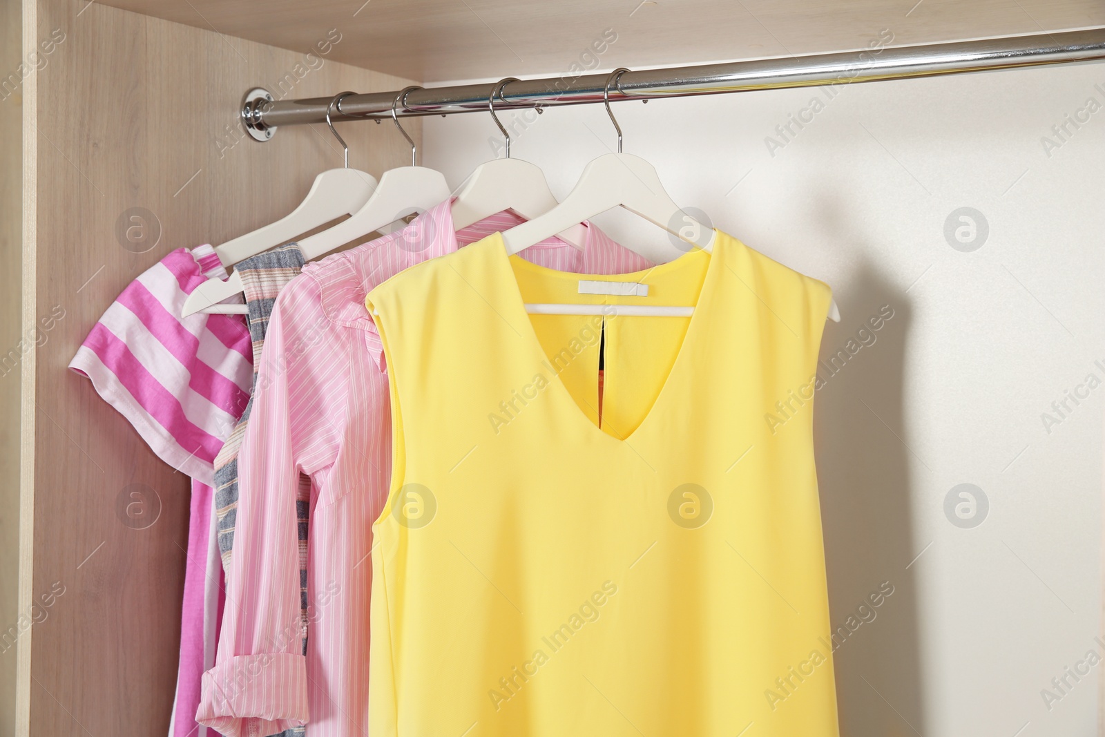 Photo of Stylish girl's clothes hanging in wardrobe, closeup