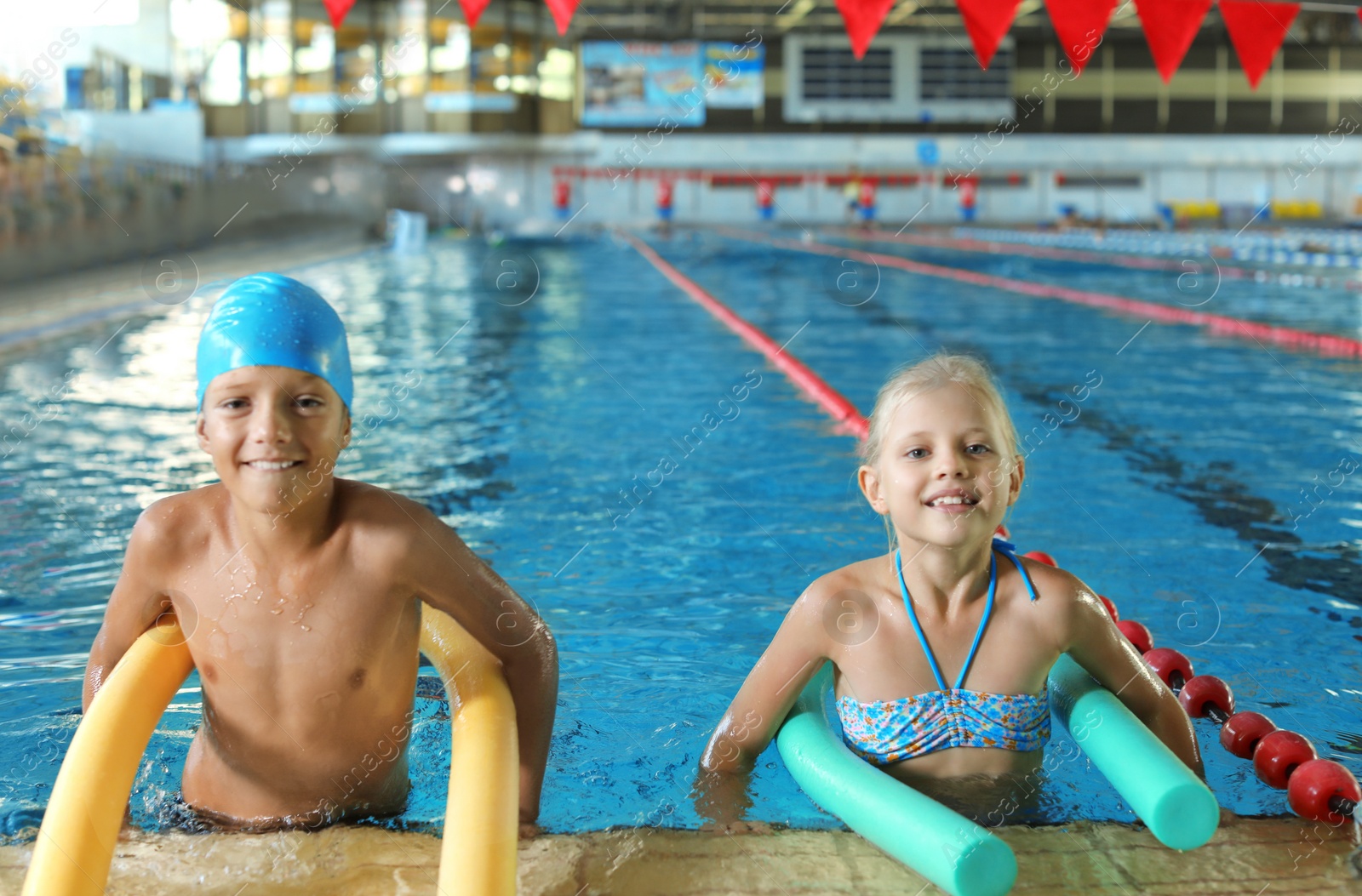 Photo of Little kids with swimming noodles in indoor pool