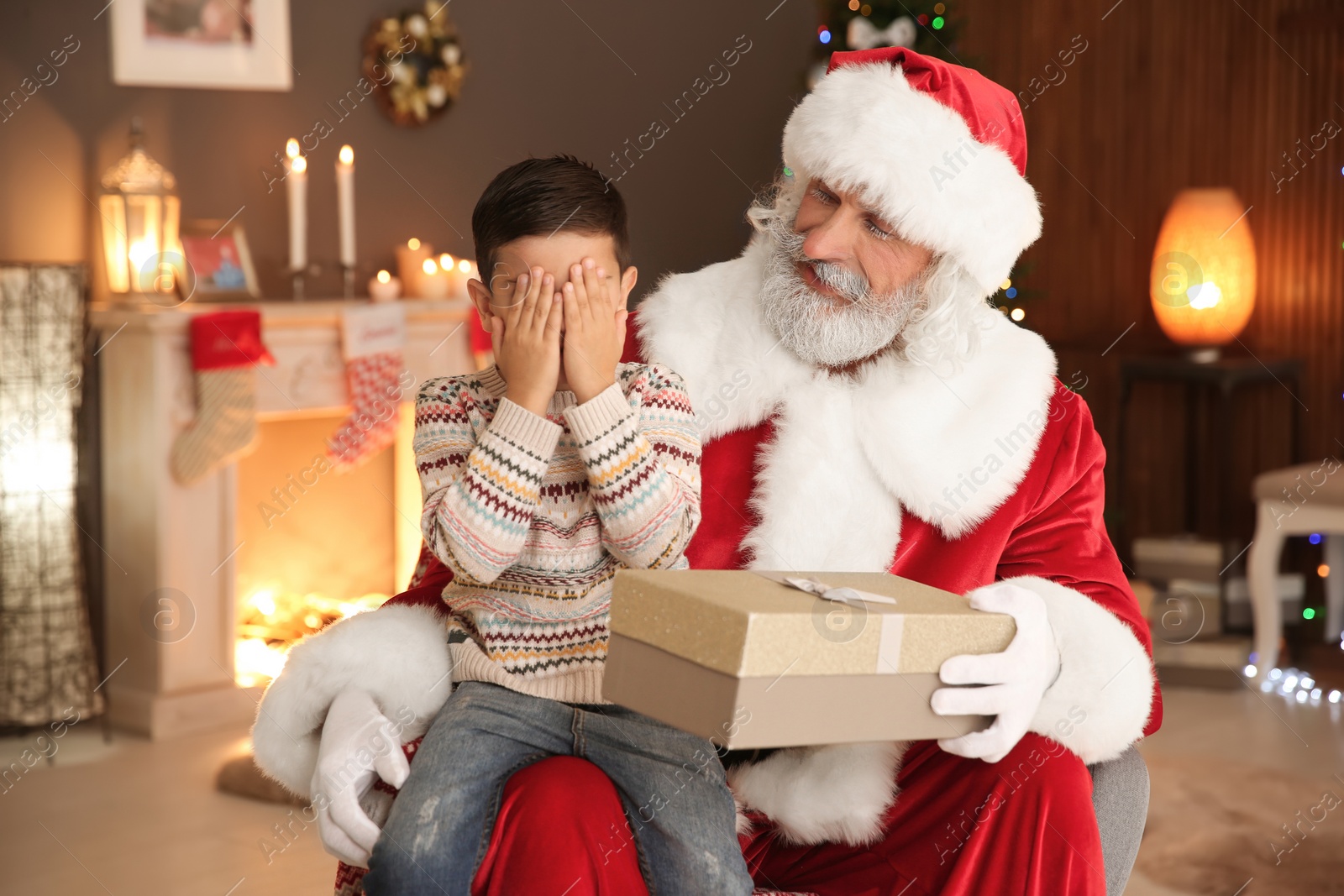 Photo of Little child with Santa Claus and Christmas gift at home