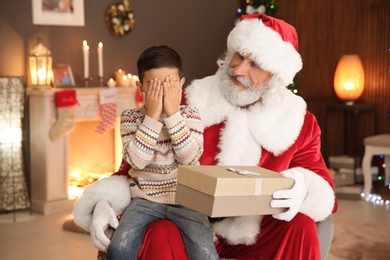 Little child with Santa Claus and Christmas gift at home