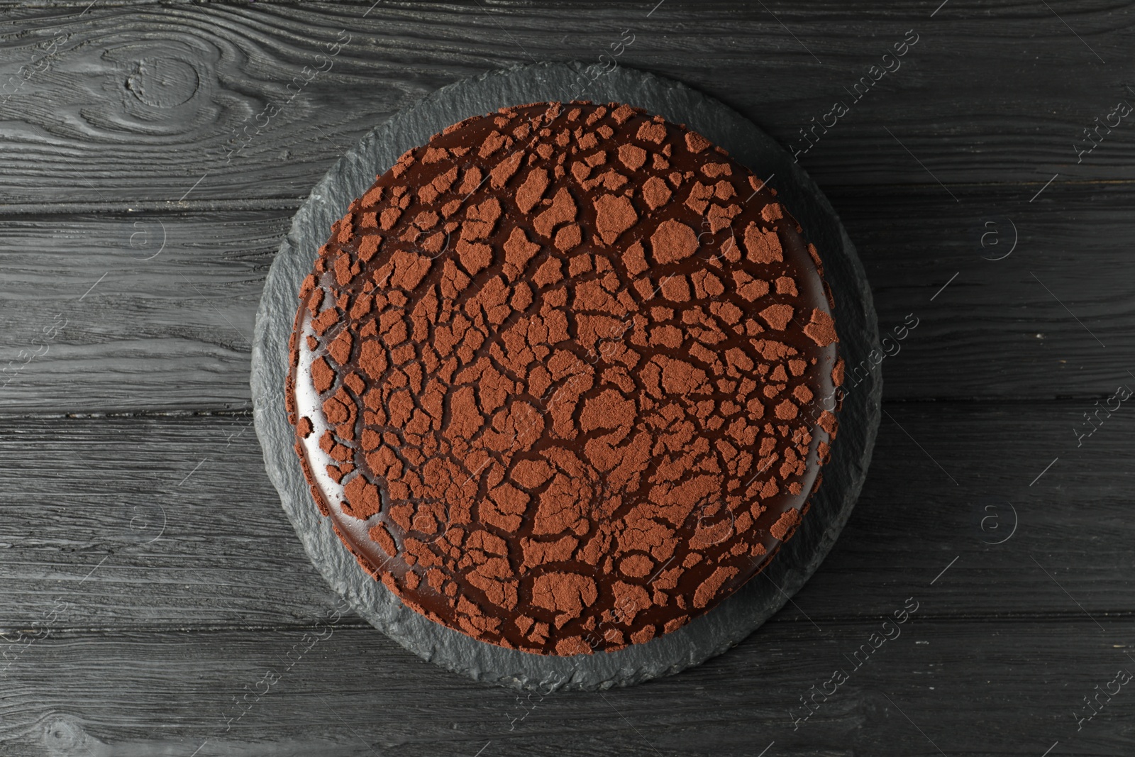 Photo of Delicious chocolate truffle cake on black wooden table, top view