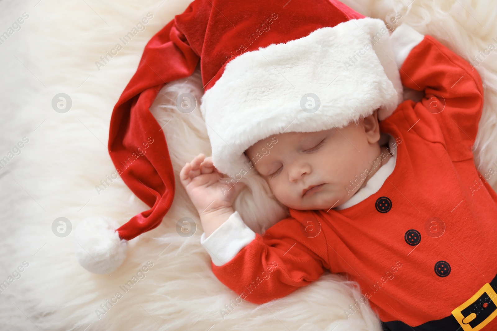 Photo of Cute baby in Christmas costume sleeping on fur rug