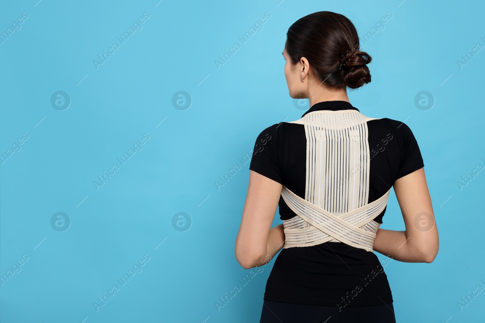 Photo of Woman with orthopedic corset on blue background, back view. Space for text