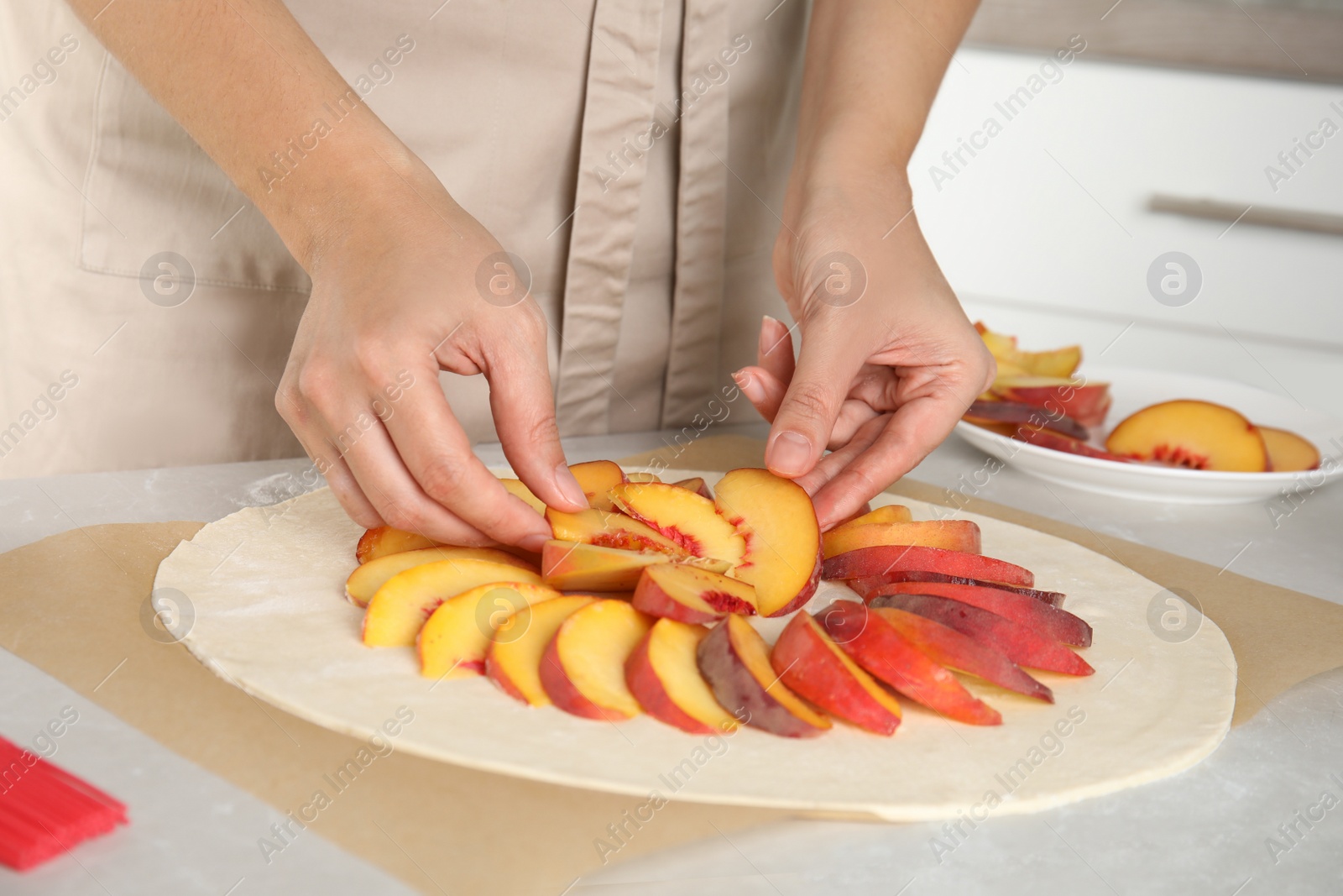 Photo of Woman making peach pie at kitchen table, closeup