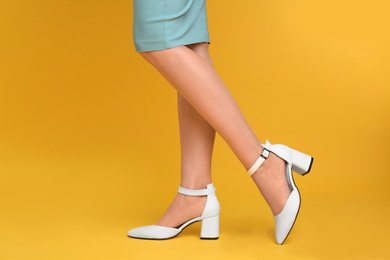 Photo of Woman wearing stylish shoes on yellow background, closeup