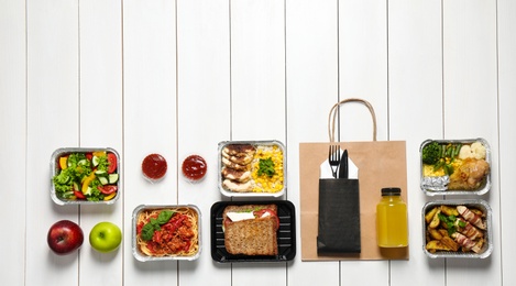 Photo of Lunchboxes on white wooden table, flat lay. Healthy food delivery