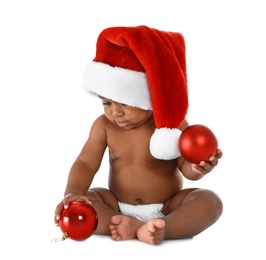 Cute African-American baby wearing Santa hat with Christmas decorations on white background