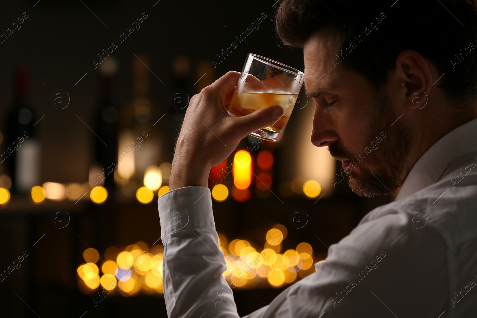 Photo of Man with glass of whiskey against blurred lights