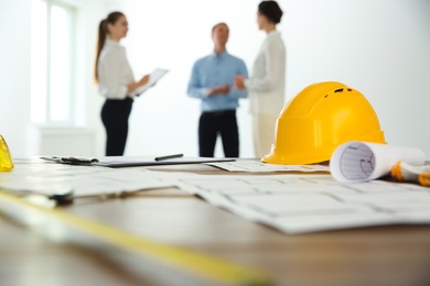 Colleagues in office, focus on table with construction drawings and tools