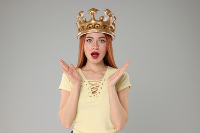 Photo of Emotional young woman with inflatable crown on light grey background