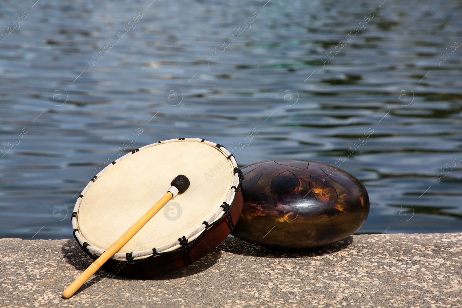 Photo of Different drums and drumstick near sea. Percussion musical instruments