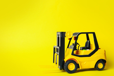 Photo of Toy forklift on yellow background, space for text. Logistics and wholesale concept