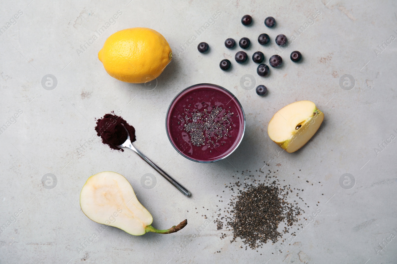 Photo of Flat lay composition with ingredients for delicious acai cocktail and glass of juice on gray table