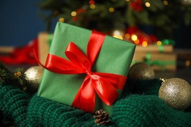 Photo of Beautiful Christmas gift box on green knitted fabric, closeup