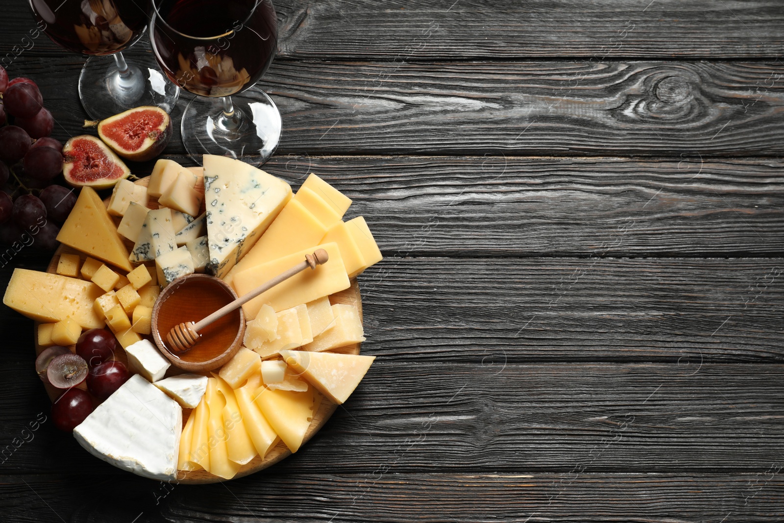 Photo of Different types of delicious cheese served on black wooden table, top view. Space for text