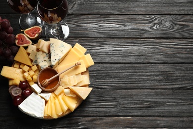 Different types of delicious cheese served on black wooden table, top view. Space for text