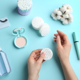 Woman with cotton pads and cosmetic on color background, top view