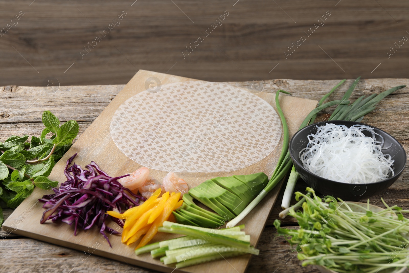 Photo of Rice paper and other ingredients for spring rolls on wooden table