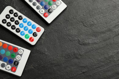 Photo of Remote controls on black table, flat lay. Space for text